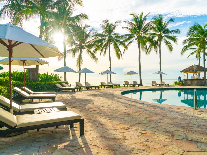 Umbrella and chair around swimming pool in resort hotel for leisure travel and vacation neary sea ocean beach at sunset or sunrise time